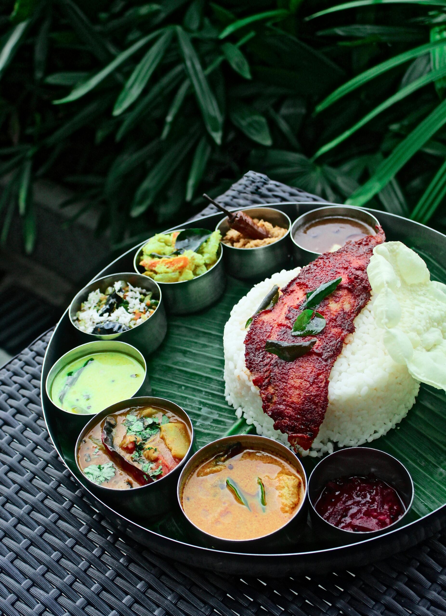 Delicious Kerala rice meal with assorted curries and fried fish served on a banana leaf.