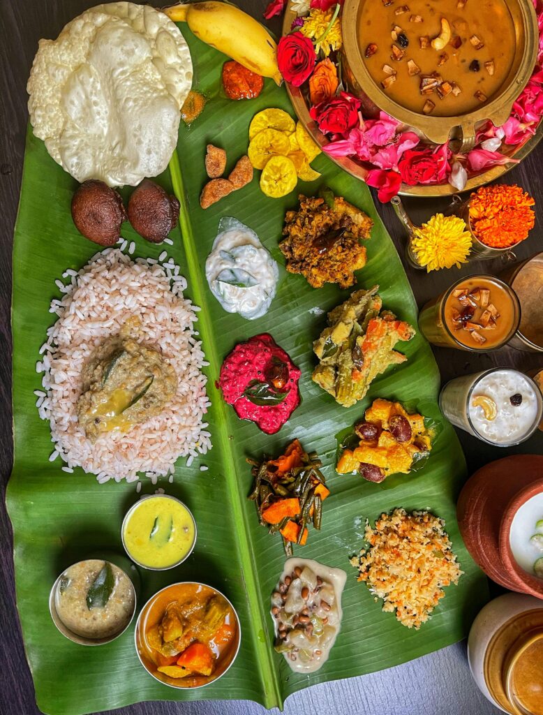 An elaborate South Indian meal with various dishes artfully arranged on a banana leaf, showcasing vibrant colors and textures.