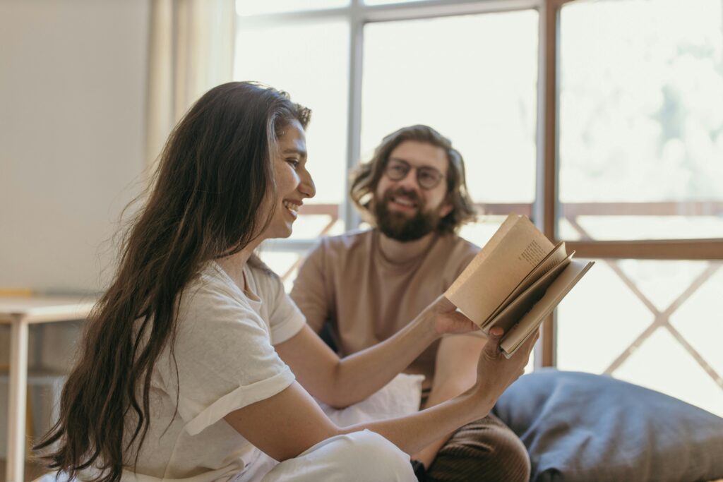 Couple seated indoors sharing a joyful moment with vintage books and laughter.